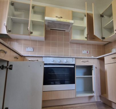 Modern kitchen with open cabinets, oven, and tiled backsplash.